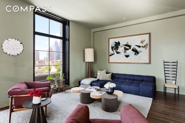 living area with a view of city, baseboards, wood finished floors, and floor to ceiling windows