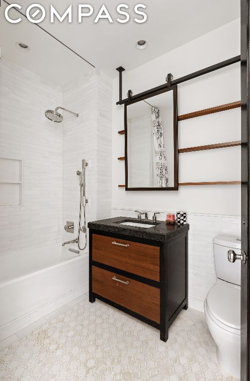 full bathroom featuring toilet, tiled shower / bath combo, tile walls, and vanity