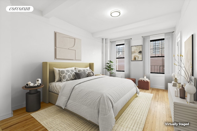bedroom with light wood-style floors and beamed ceiling