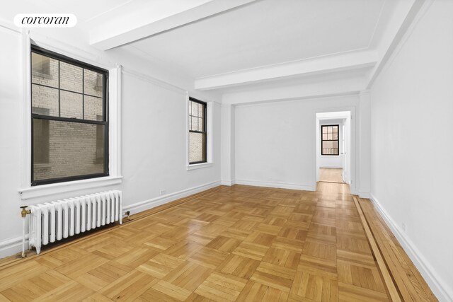 empty room featuring radiator, baseboards, visible vents, and beamed ceiling