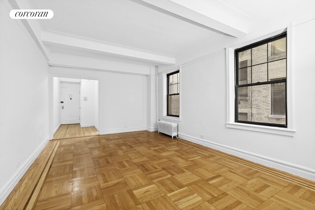 unfurnished room with beam ceiling, radiator heating unit, visible vents, and baseboards