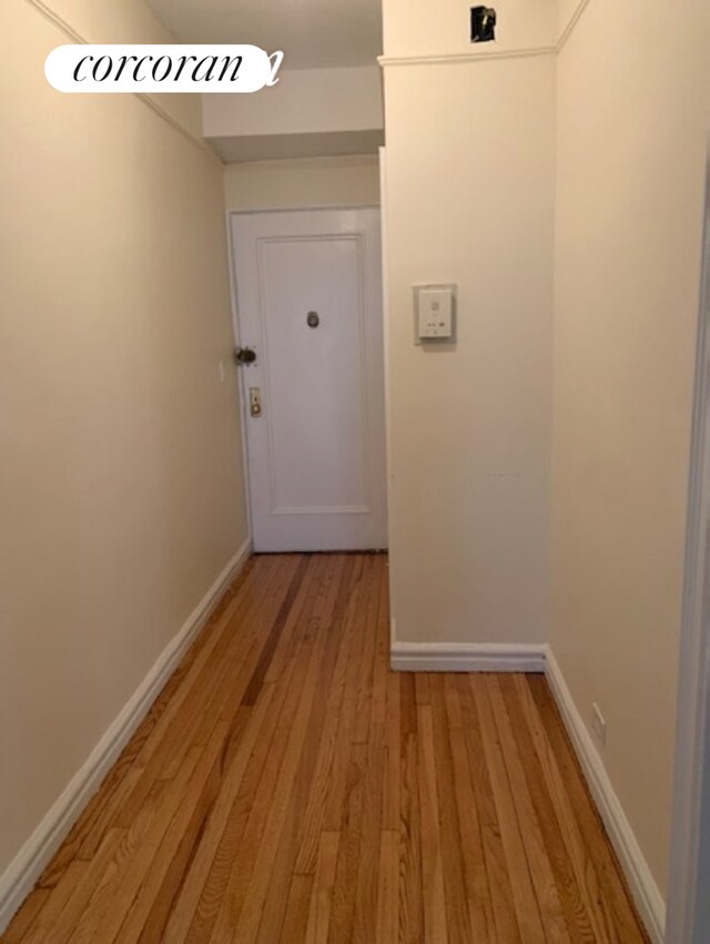 hall featuring light wood-style flooring and baseboards