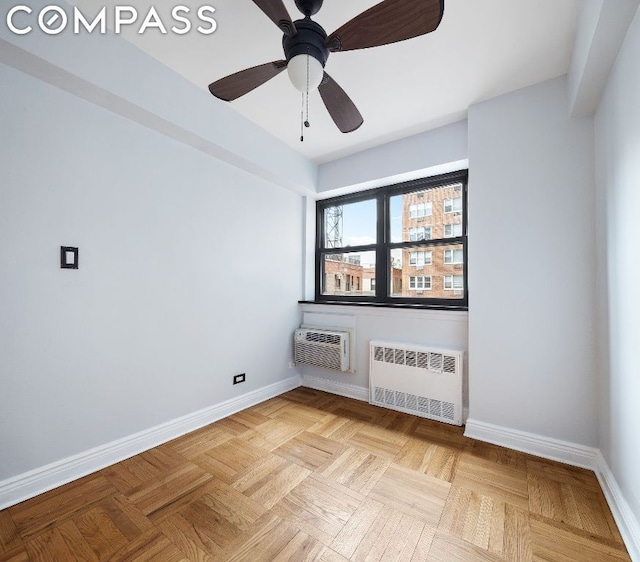 spare room featuring ceiling fan, light parquet flooring, radiator heating unit, and a wall mounted air conditioner