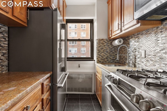 kitchen with backsplash, dark tile patterned flooring, sink, and stainless steel appliances