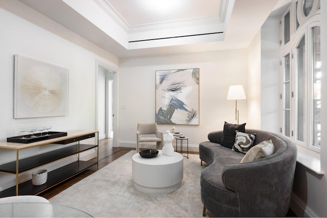 living area featuring a tray ceiling, crown molding, baseboards, and wood finished floors