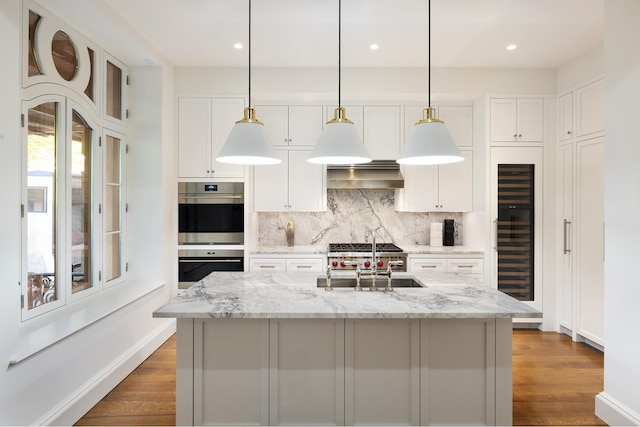 kitchen featuring wine cooler, tasteful backsplash, stainless steel double oven, a sink, and exhaust hood