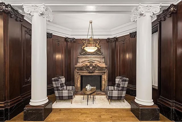 sitting room with decorative columns, a fireplace, wood finished floors, and crown molding