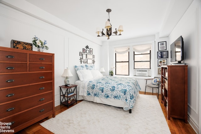 bedroom featuring cooling unit, wood-type flooring, and a chandelier