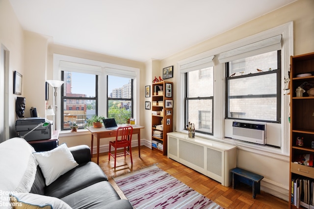 office space with cooling unit, a healthy amount of sunlight, radiator, and light parquet floors