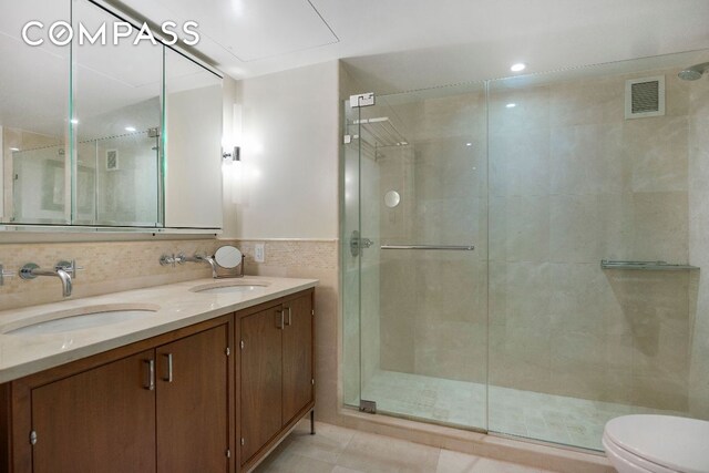 bathroom featuring toilet, walk in shower, tile walls, tile patterned floors, and vanity