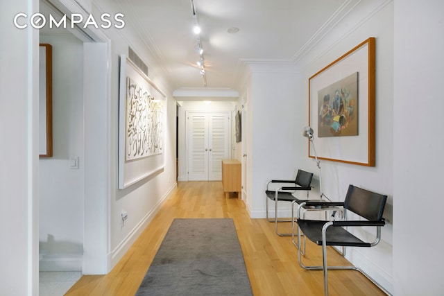 hall featuring crown molding, rail lighting, visible vents, wood finished floors, and baseboards