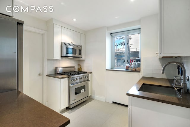 200 E 66th St Unit B205, New York City, NY 10065 - kitchen featuring stainless steel appliances, dark countertops, white cabinets, tasteful backsplash, and recessed lighting