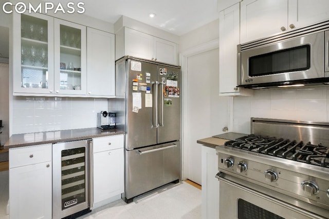 kitchen featuring wine cooler, decorative backsplash, appliances with stainless steel finishes, and white cabinetry