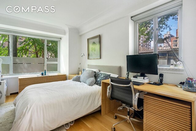 bedroom with multiple windows, ornamental molding, and wood-type flooring