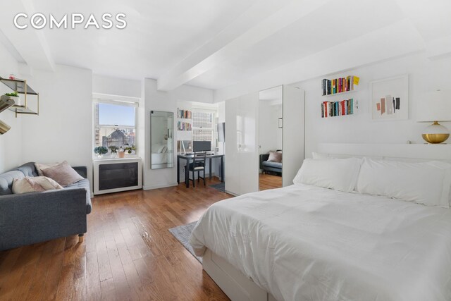 bedroom with beamed ceiling and hardwood / wood-style flooring