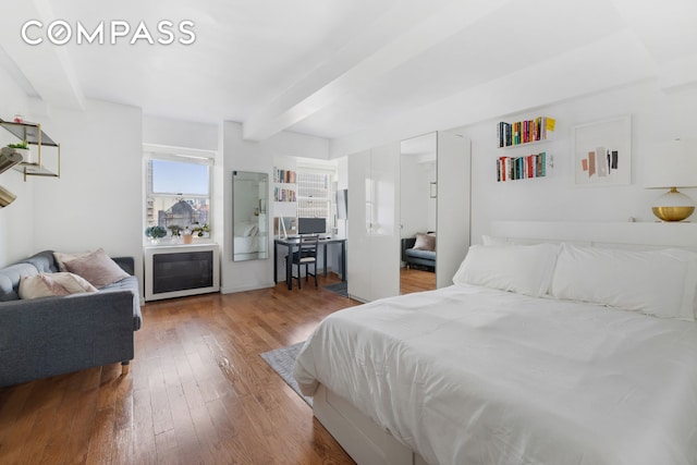 bedroom with wood-type flooring and beamed ceiling