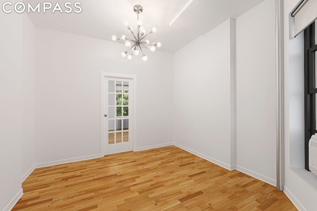 empty room with a chandelier and light hardwood / wood-style flooring