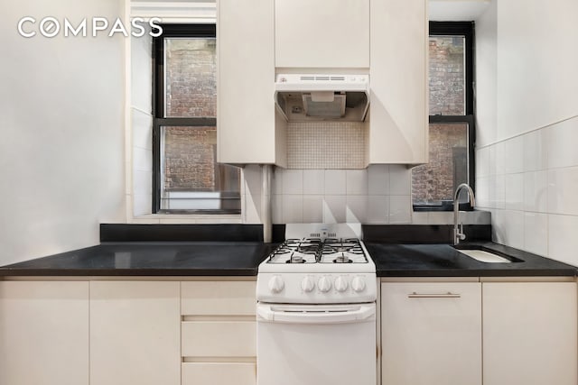 28 Perry St Unit 4E, New York City, NY 10014 - kitchen with white gas range, a sink, backsplash, dark countertops, and extractor fan