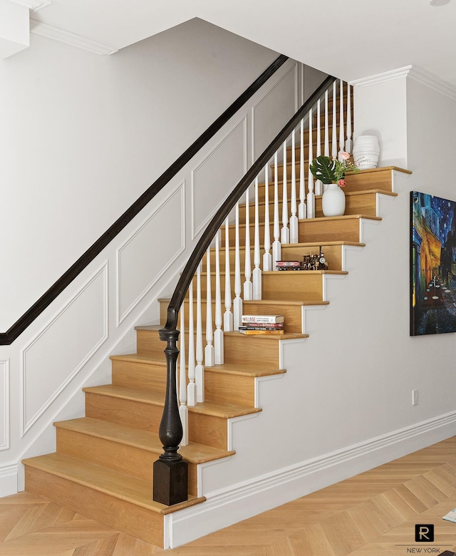 stairway with baseboards, ornamental molding, and a decorative wall