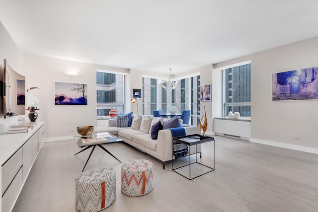 living room with light wood-style flooring, baseboards, and a chandelier