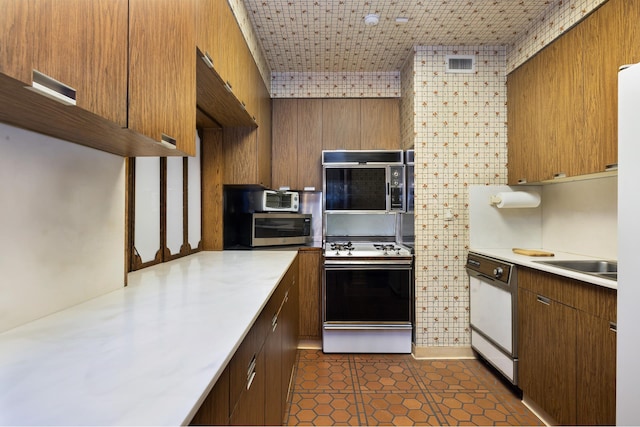 kitchen with white dishwasher, visible vents, light countertops, stainless steel microwave, and gas stove