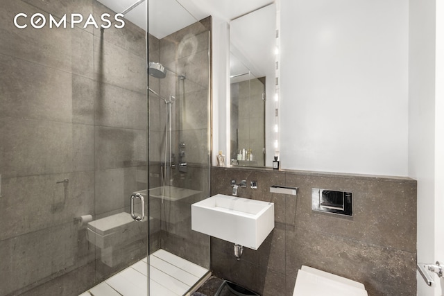 350 E 82nd St Unit 14Ab, New York City, NY 10028 - bathroom featuring tile walls, toilet, a stall shower, and a sink