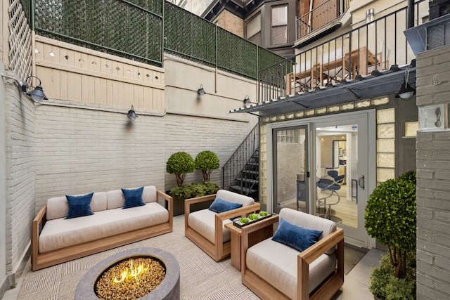 view of patio / terrace with an outdoor living space with a fire pit and a balcony