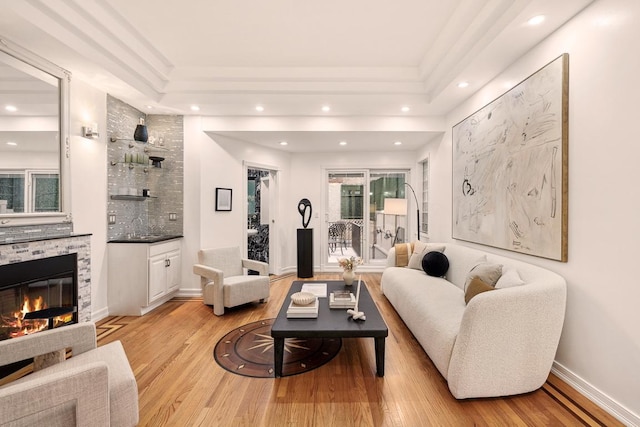 living room featuring light hardwood / wood-style floors, a fireplace, and a tray ceiling