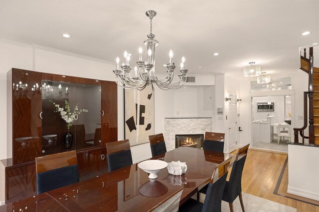 kitchen featuring pendant lighting, crown molding, built in appliances, a wall mounted air conditioner, and white cabinetry