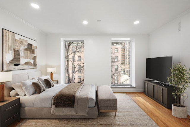 bedroom with crown molding, light hardwood / wood-style floors, and multiple windows