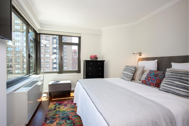 bedroom with ornamental molding and wood finished floors