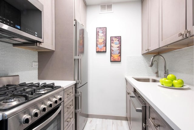 kitchen featuring appliances with stainless steel finishes, gray cabinetry, tasteful backsplash, and sink