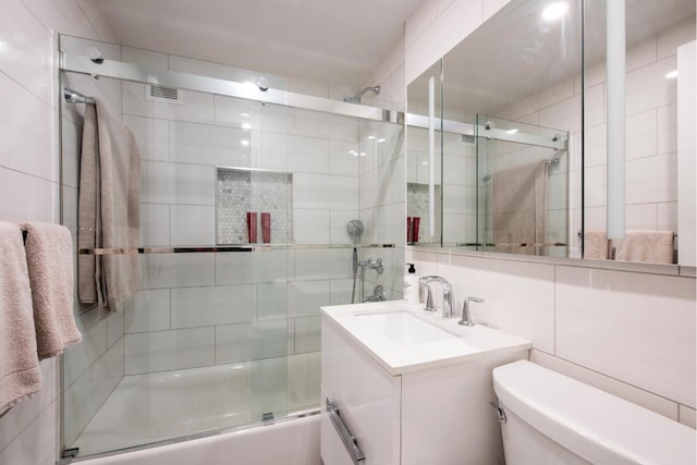 full bathroom with toilet, bath / shower combo with glass door, tile walls, vanity, and decorative backsplash