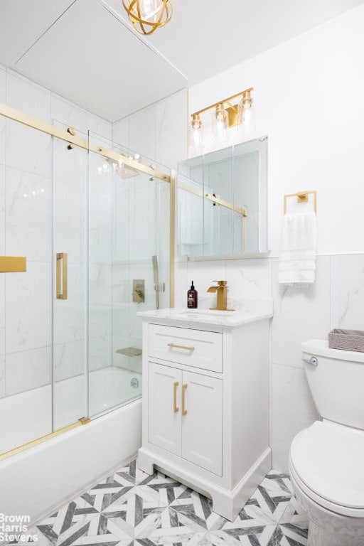 full bathroom featuring toilet, vanity, and shower / bath combination with glass door