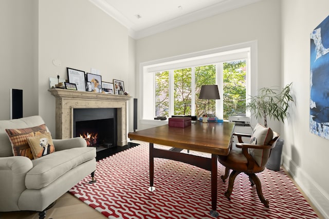 home office featuring a lit fireplace, ornamental molding, wood finished floors, and baseboards