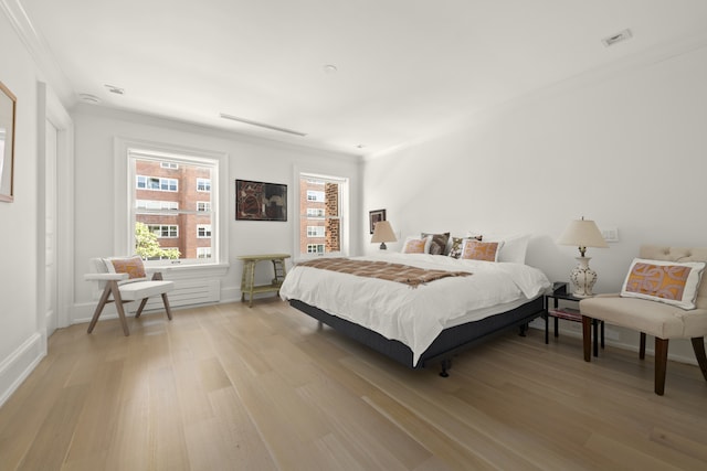 bedroom with ornamental molding, light wood-type flooring, and visible vents