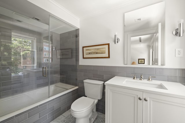 full bathroom featuring tile walls, toilet, ornamental molding, combined bath / shower with glass door, and vanity