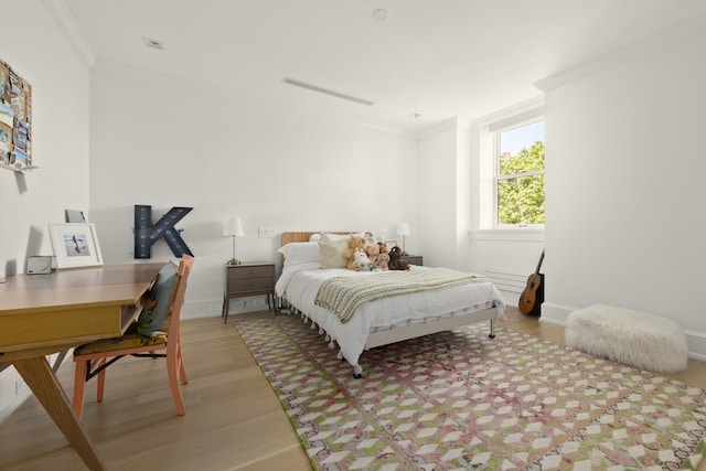 bedroom featuring light wood-style floors, baseboards, and ornamental molding