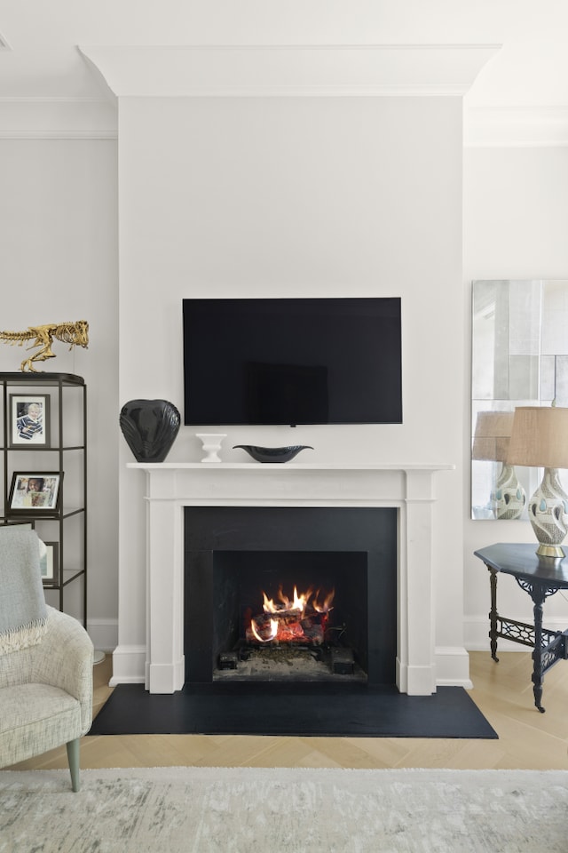 interior space with wood finished floors, a fireplace with flush hearth, baseboards, visible vents, and crown molding