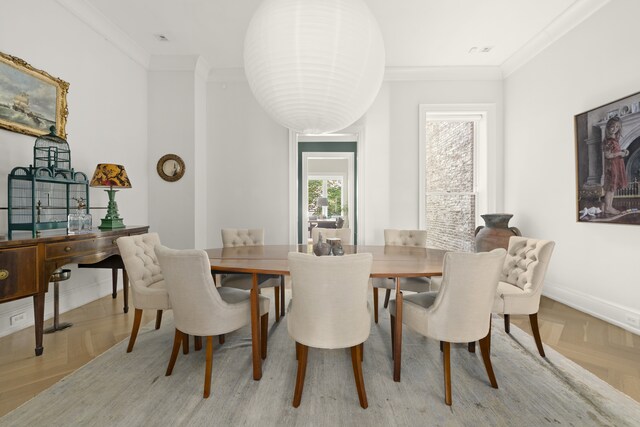 dining space with crown molding and light parquet floors