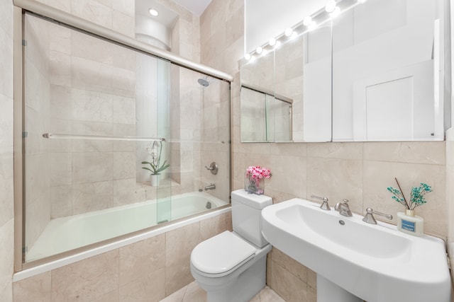 bathroom featuring toilet, tiled shower / bath combo, a sink, tile walls, and decorative backsplash