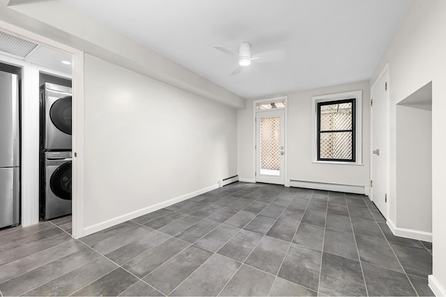 spare room with stacked washer / dryer, baseboards, ceiling fan, baseboard heating, and a baseboard radiator