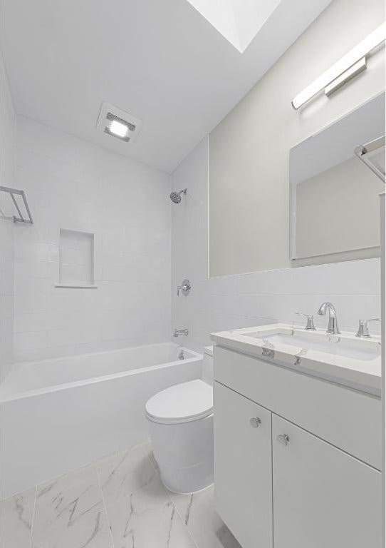 full bathroom with toilet, vanity, a skylight, and tiled shower / bath