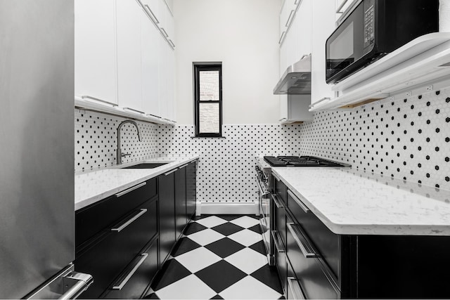 kitchen featuring a sink, appliances with stainless steel finishes, under cabinet range hood, dark floors, and dark cabinets