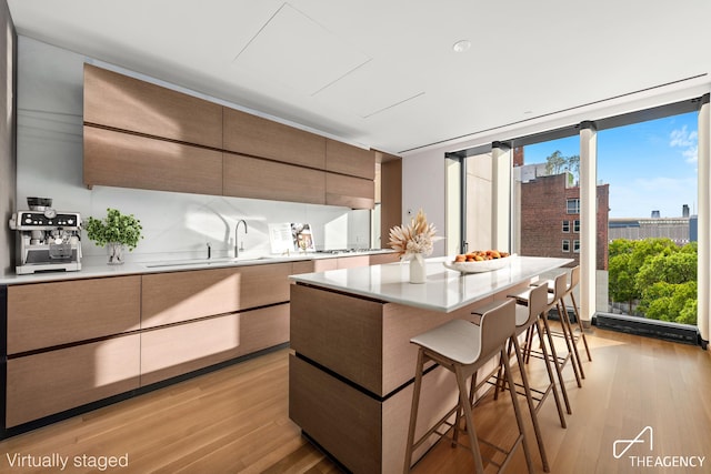 kitchen featuring a breakfast bar, light countertops, light wood-style floors, a kitchen island, and modern cabinets