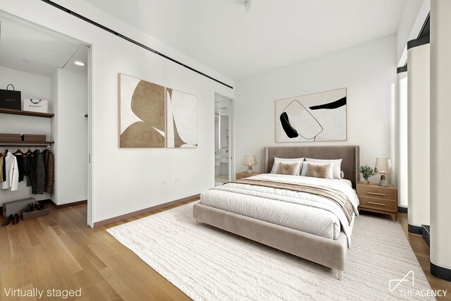 bedroom featuring ensuite bath, wood-type flooring, and a closet