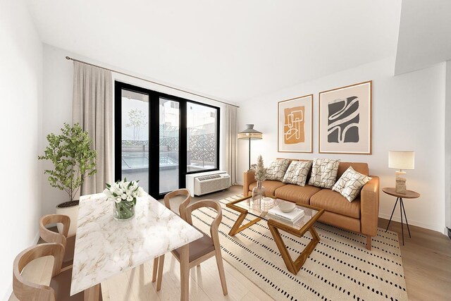 living room with a wall unit AC and light hardwood / wood-style flooring