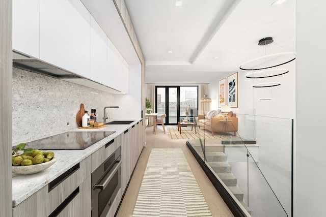 kitchen featuring white cabinetry, sink, backsplash, stainless steel oven, and black electric cooktop