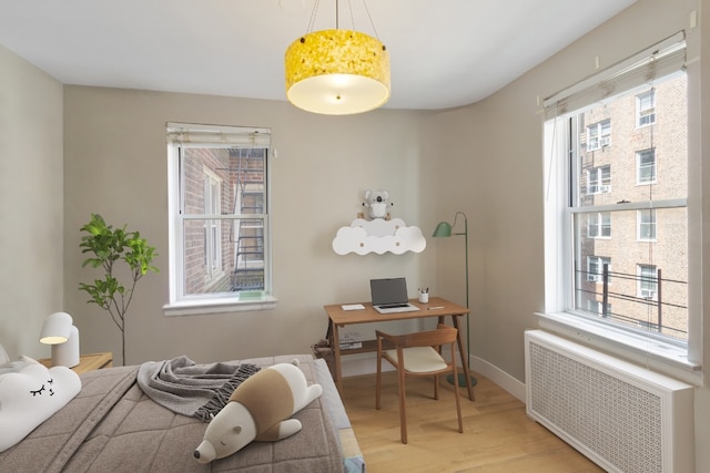 bedroom with multiple windows, radiator, and light hardwood / wood-style floors