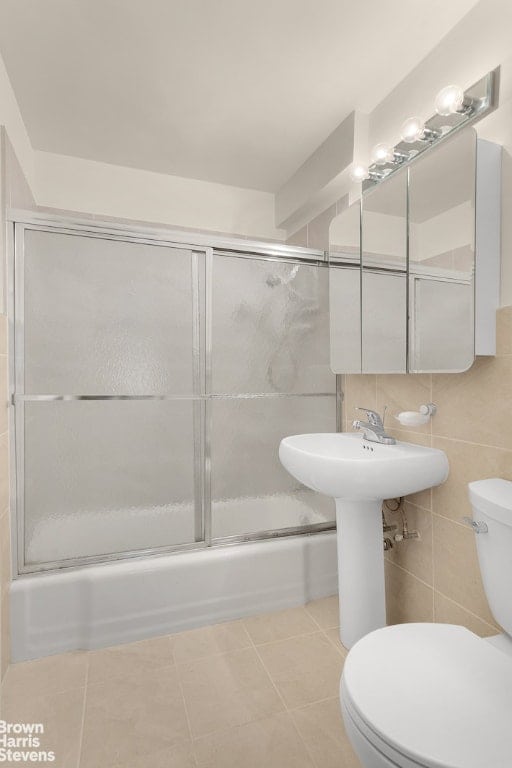 bathroom with toilet, tasteful backsplash, tile walls, tile patterned flooring, and enclosed tub / shower combo